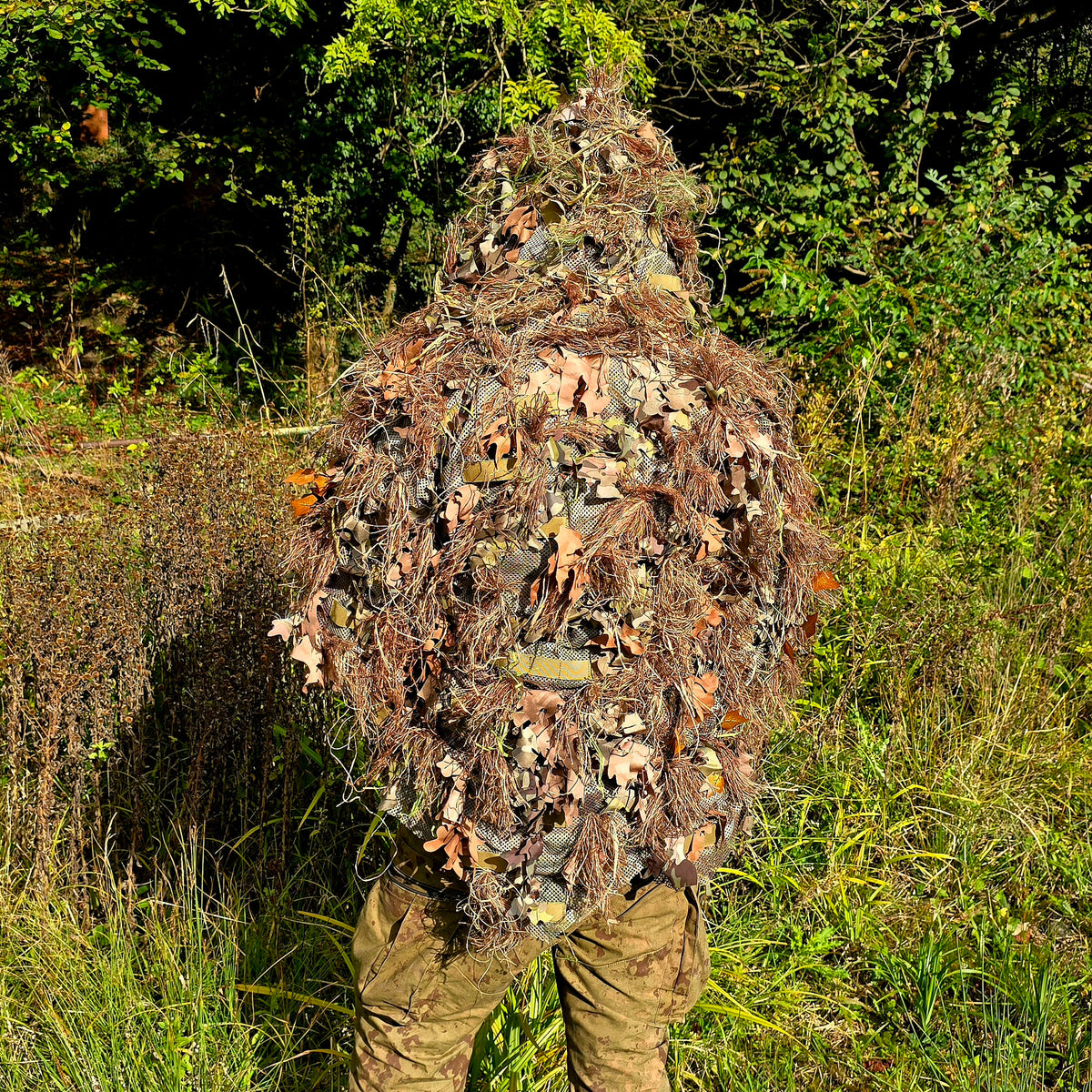 Deadground Revenant ghillie concealment system with layered leaf and twine camouflage materials for multi-environment concealment.